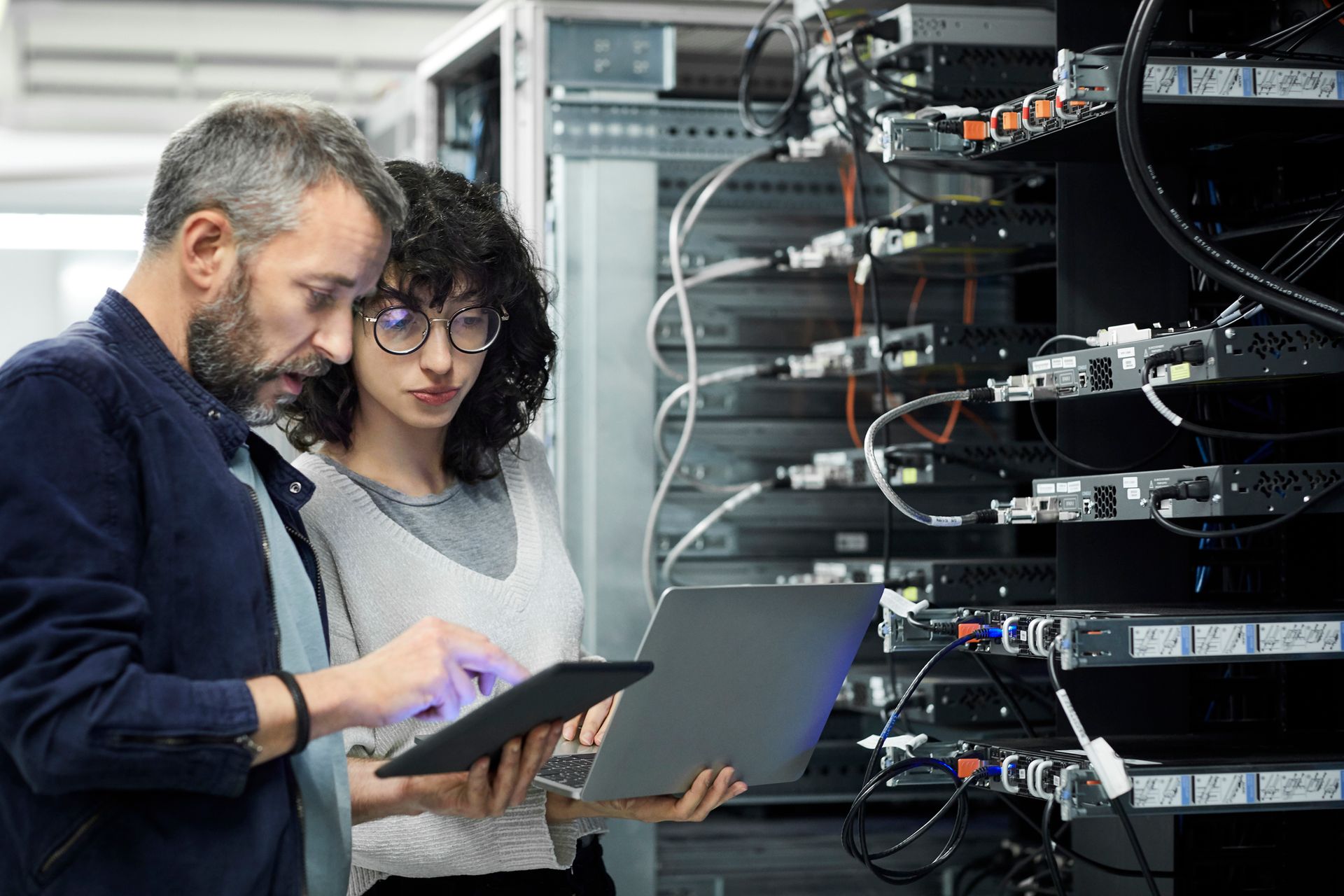 Technician showing digital tablet to coworker in server room - Computer IT Services In Banner Elk