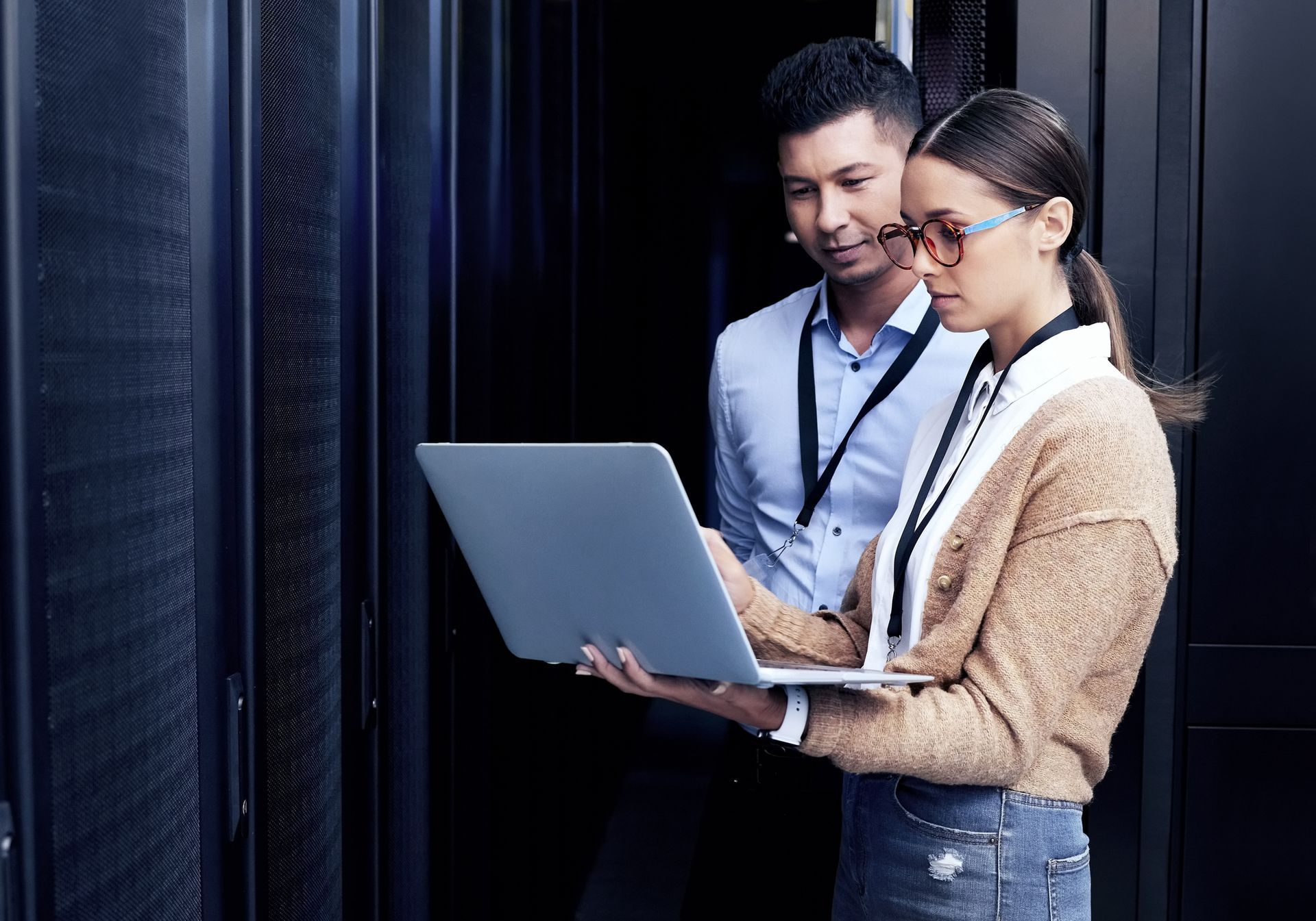 Two technicians working together in a server room, showcasing excellent IT managed services. Two technicians working together in a server room, showcasing excellent IT managed services.