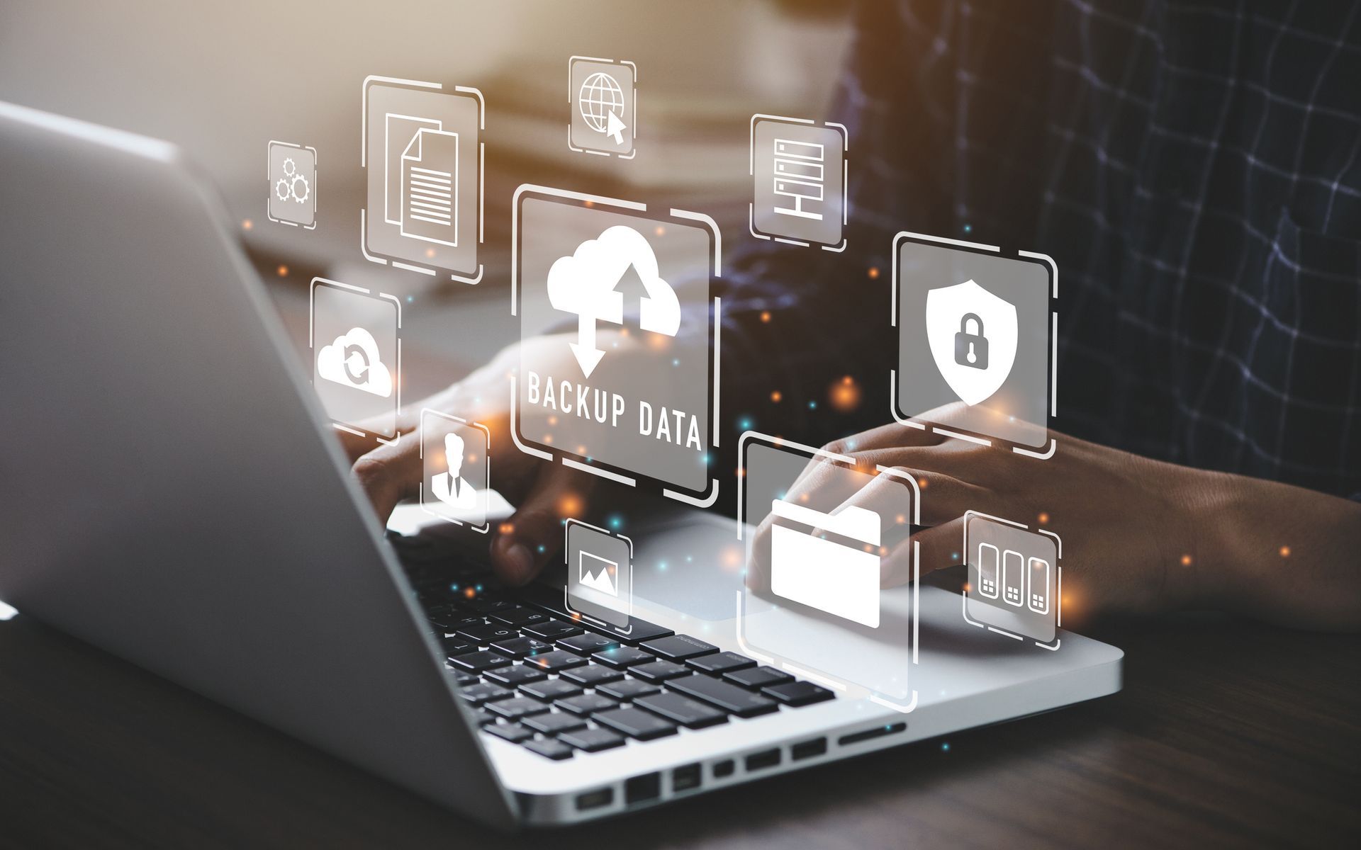 Person typing on laptop with data backup and security icons overlay.