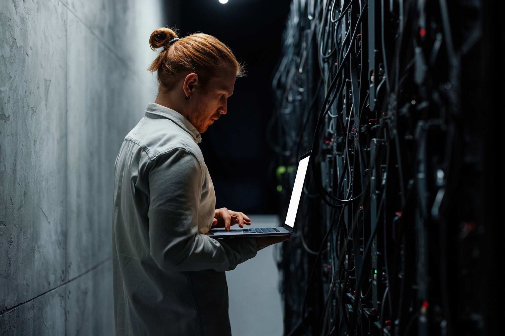 Male IT specialist working on a laptop in a server room, showcasing quality managed IT services.