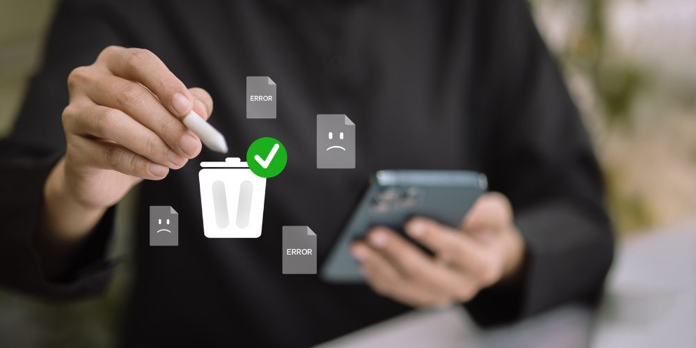Person using a stylus to delete files on a phone, trash can and check mark icon overlay.