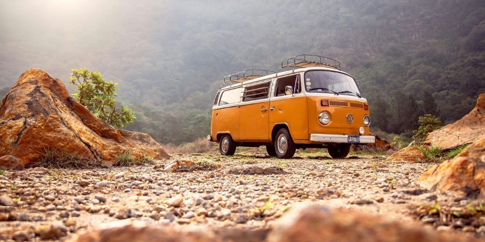 A yellow van is parked on a rocky road in the mountains.