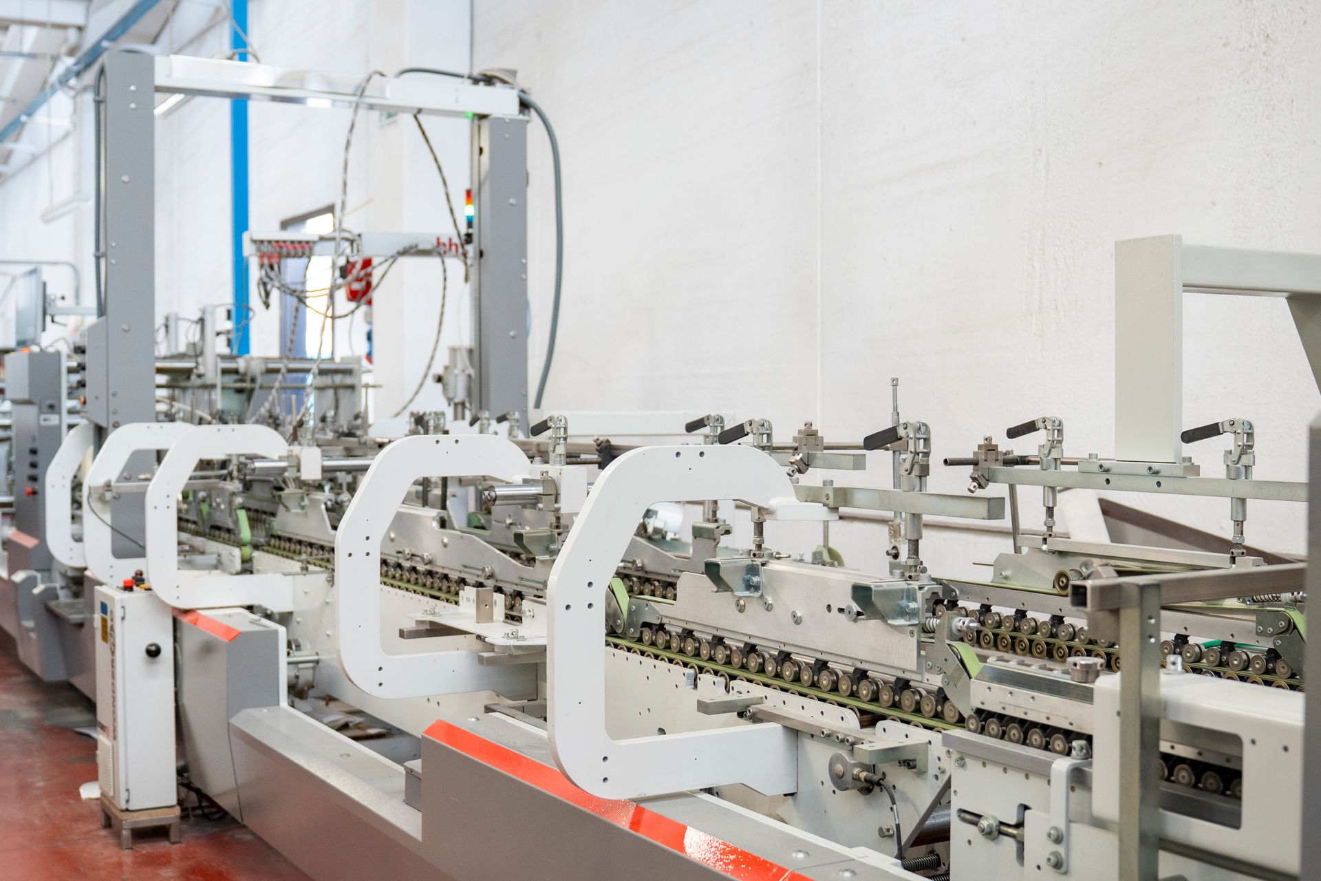 Macchina trasportatrice industriale automatizzata in una fabbrica, con telaio in metallo bianco e componenti mobili.