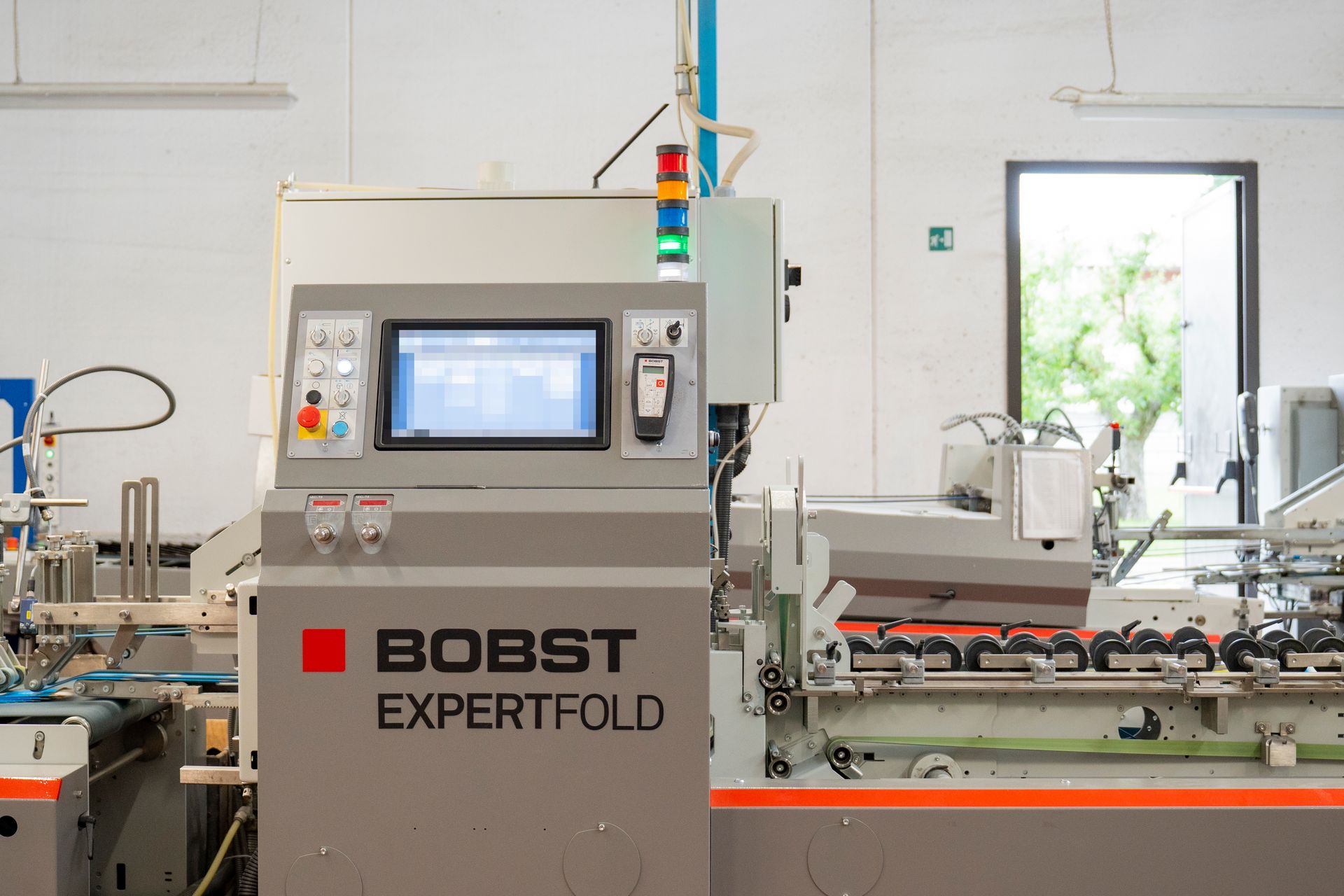 Macchina piegatrice industriale BOBST ExpertFold in un luminoso laboratorio di fabbrica.