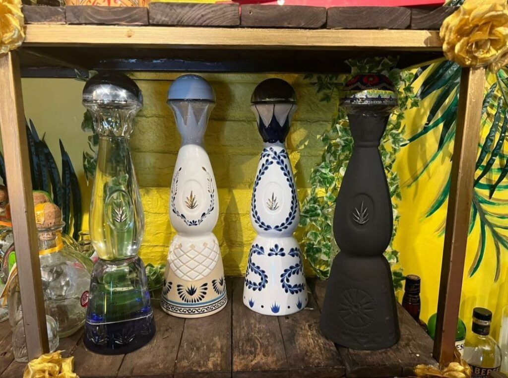 Four candles are sitting on a wooden shelf in front of a yellow wall.