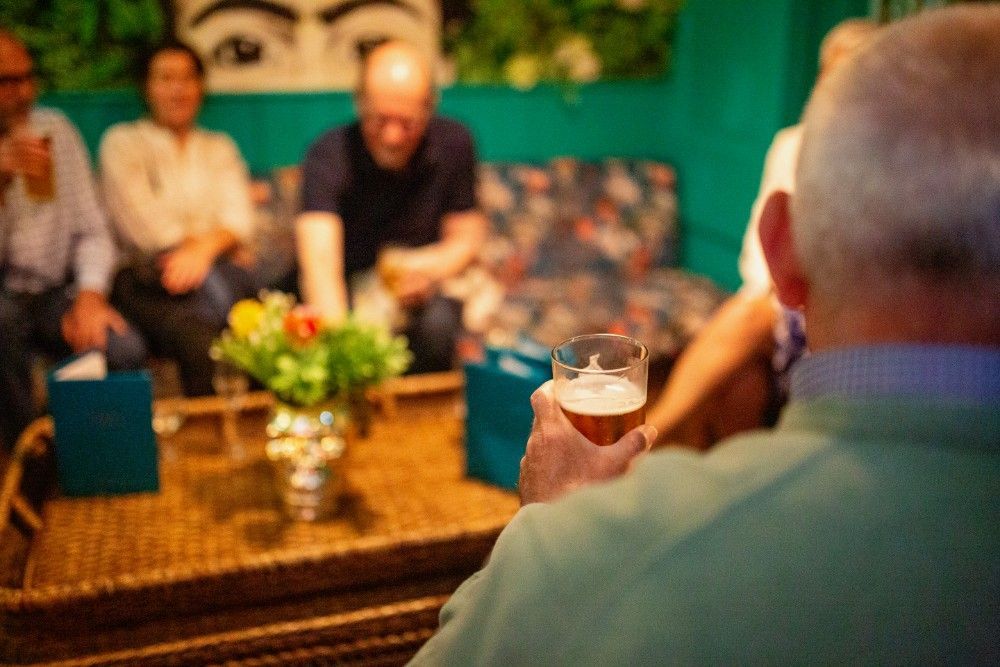 A man is holding a glass of beer in front of a group of people.