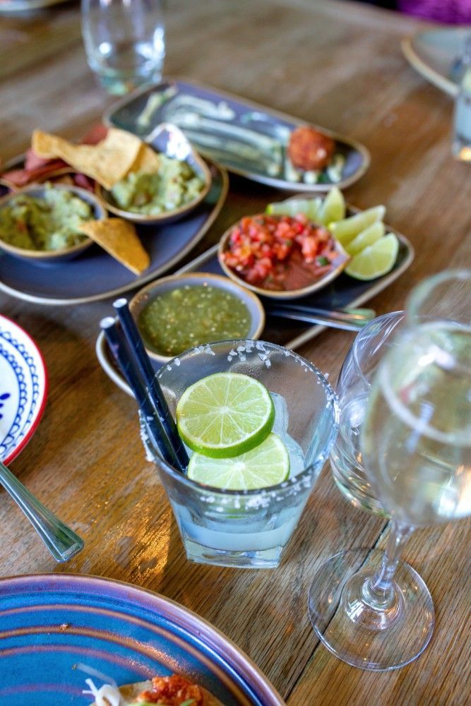 A table topped with plates of food and a glass of margarita.