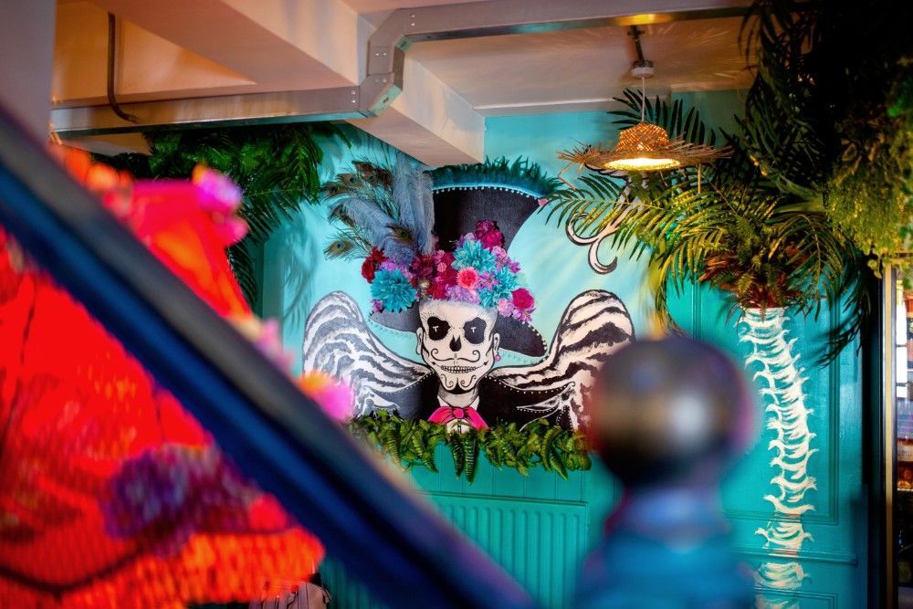 A mural of a skeleton wearing a top hat and flowers on a wall.