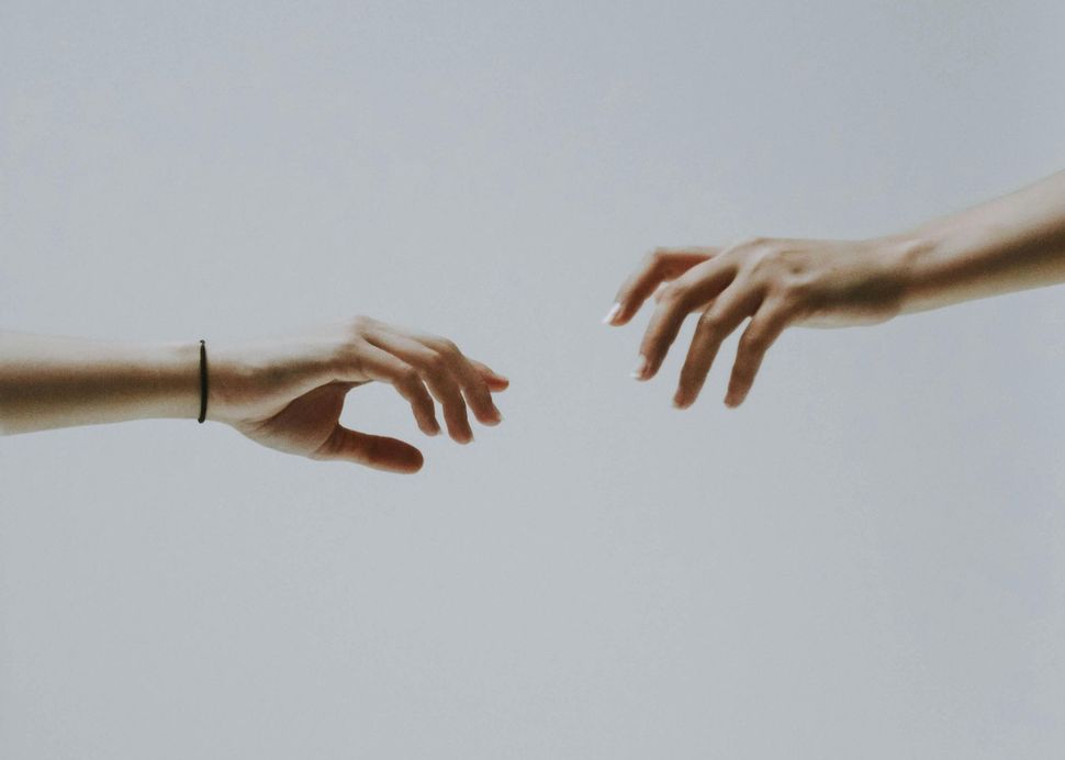 Two hands are reaching for each other on a white background.