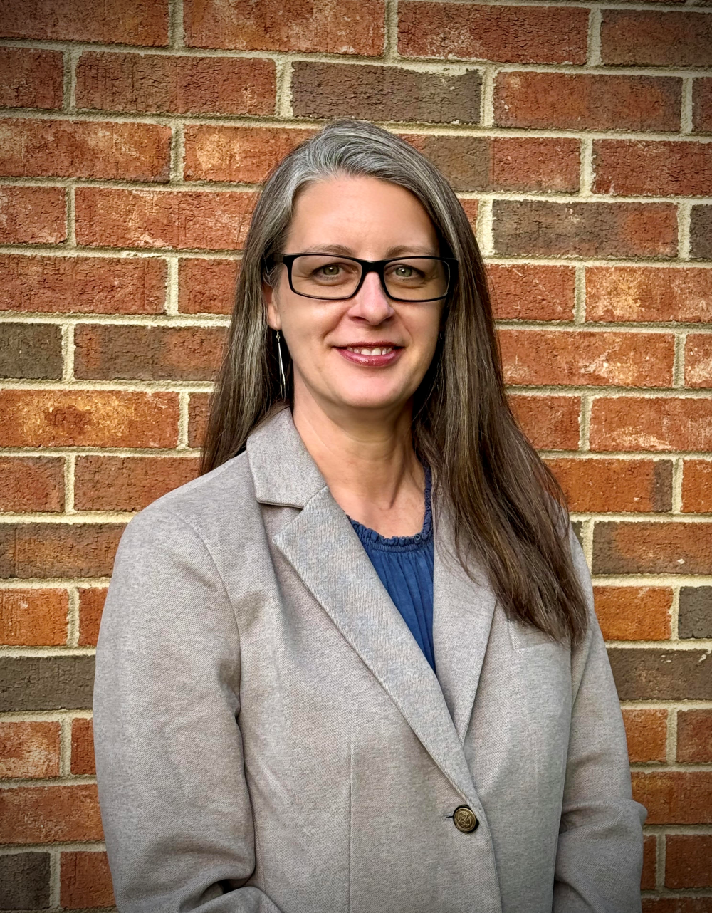 photo of Candice Faulkenberry, professional headshot with brick wall