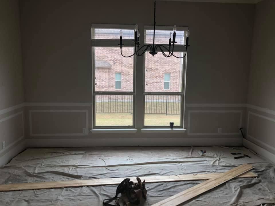 An empty dining room with a chandelier and a lot of windows.