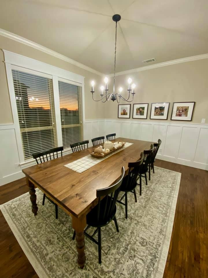 A dining room with a long wooden table and chairs and a chandelier.