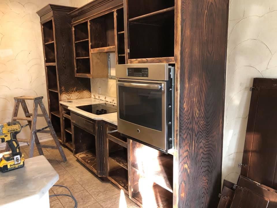 A kitchen is being remodeled with wooden cabinets and a stainless steel oven.