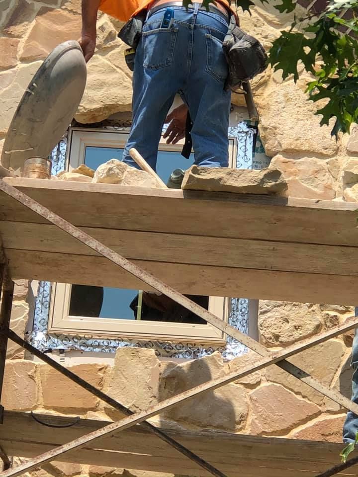 A man is standing on a scaffolding working on a window