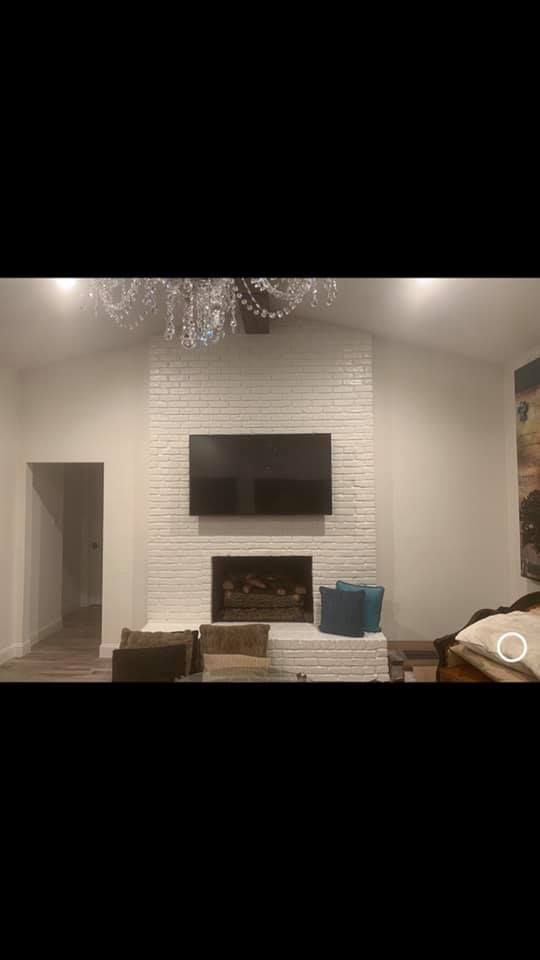 A living room with a fireplace and a flat screen tv on the wall.