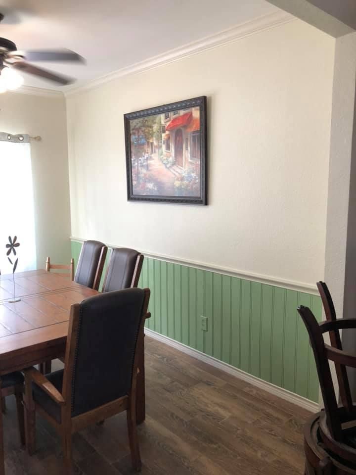 A dining room with a table and chairs and a picture on the wall.