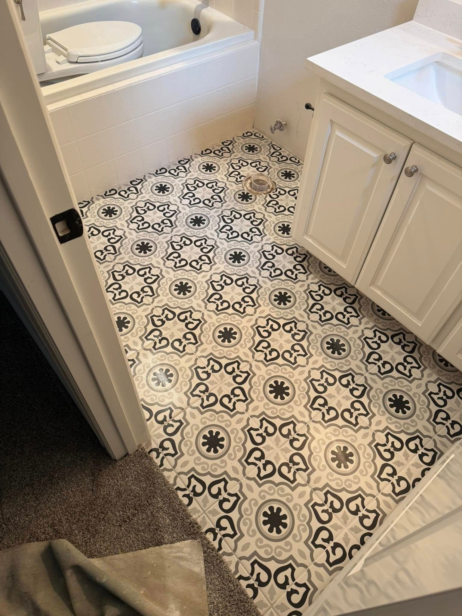 A bathroom with a black and white tile floor and a bathtub.