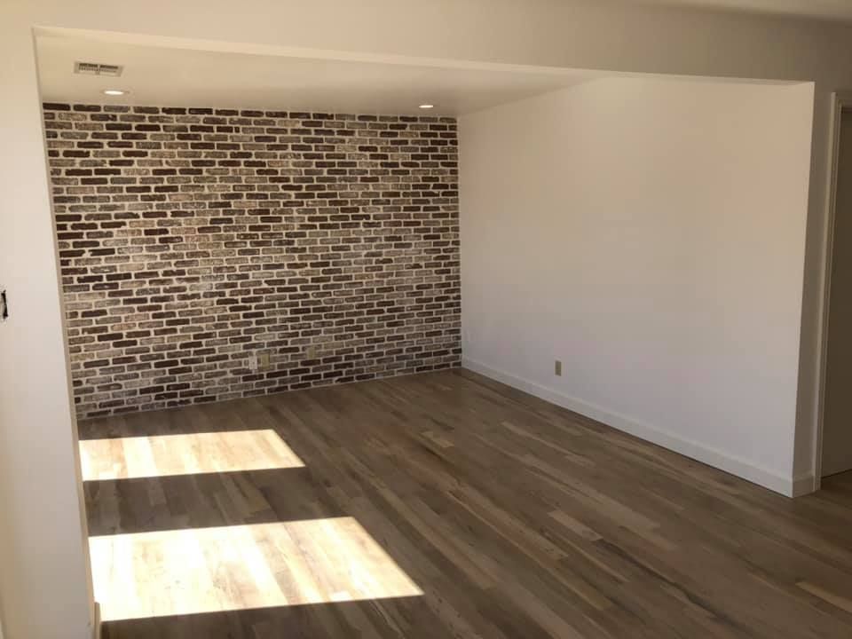 An empty room with a brick wall and wooden floor