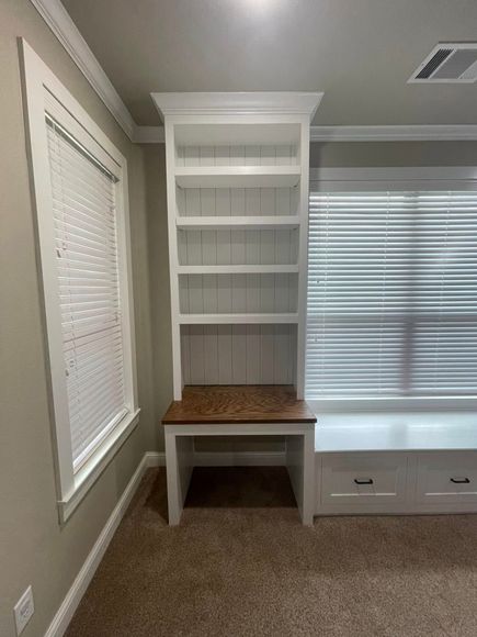 An empty room with a window seat and a bookshelf.