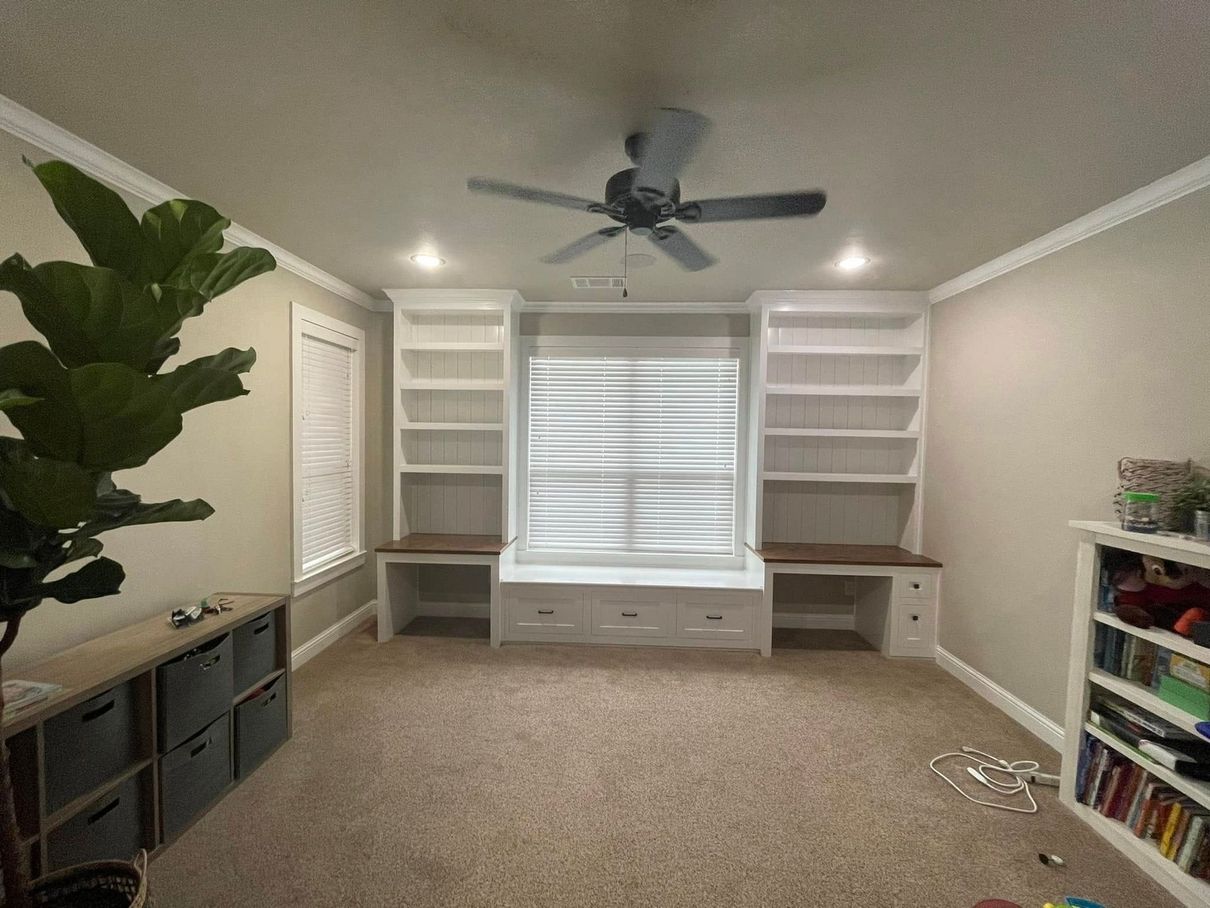A living room with a ceiling fan and a window seat.