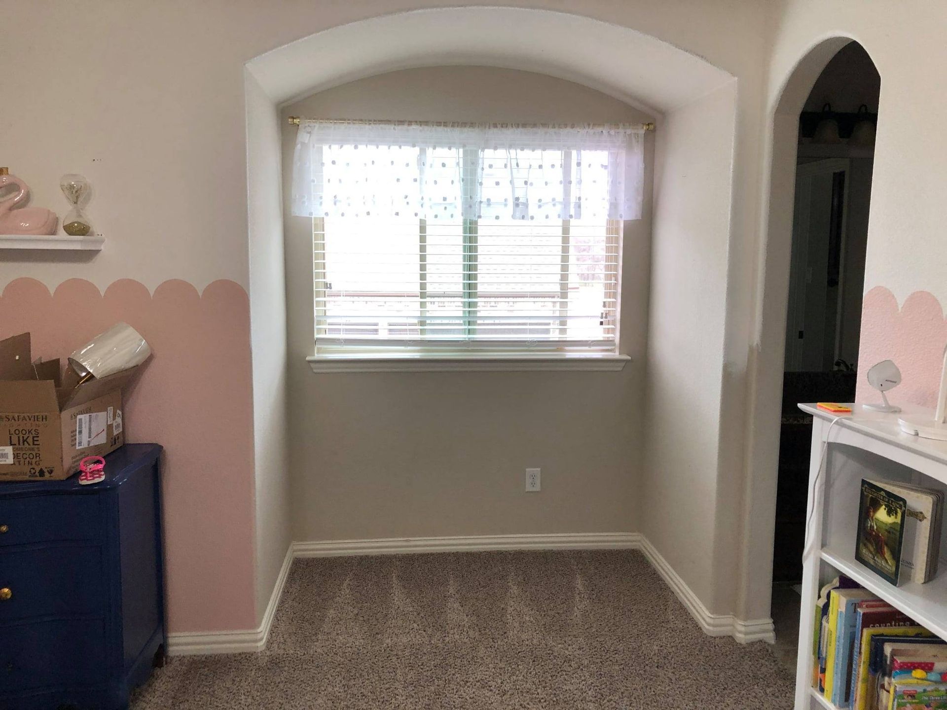 An empty room with a window and a bookshelf.