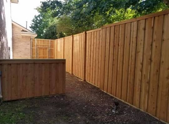 There is a wooden fence in the backyard of a house.