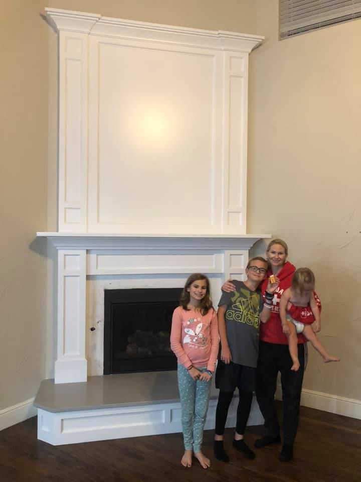 A family is standing in front of a fireplace in a living room.