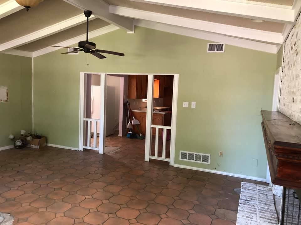 An empty living room with green walls and a ceiling fan.