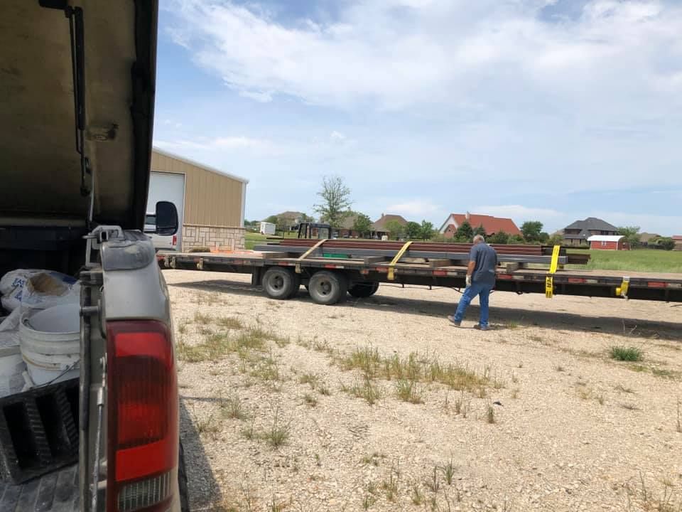 A man is standing next to a trailer in a dirt field.