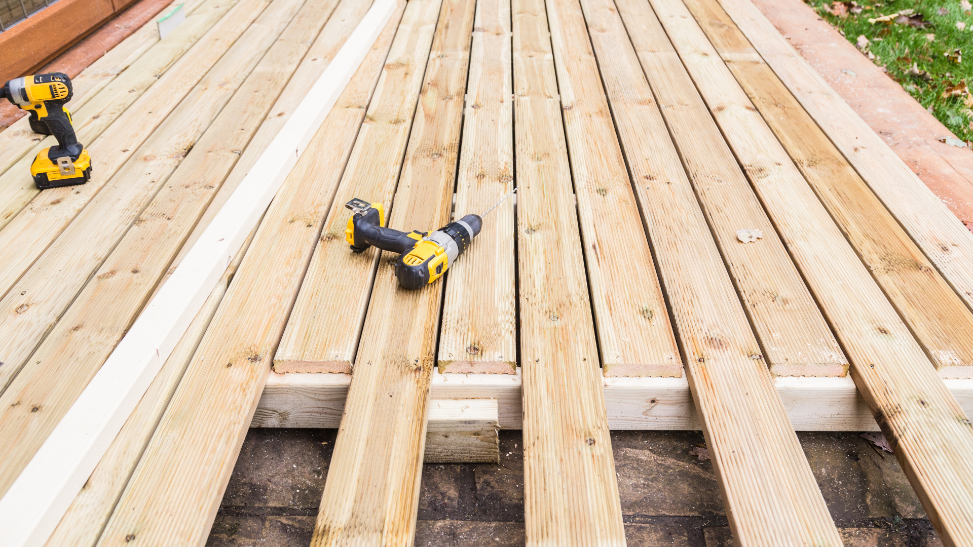 Two drills are sitting on top of a wooden deck.
