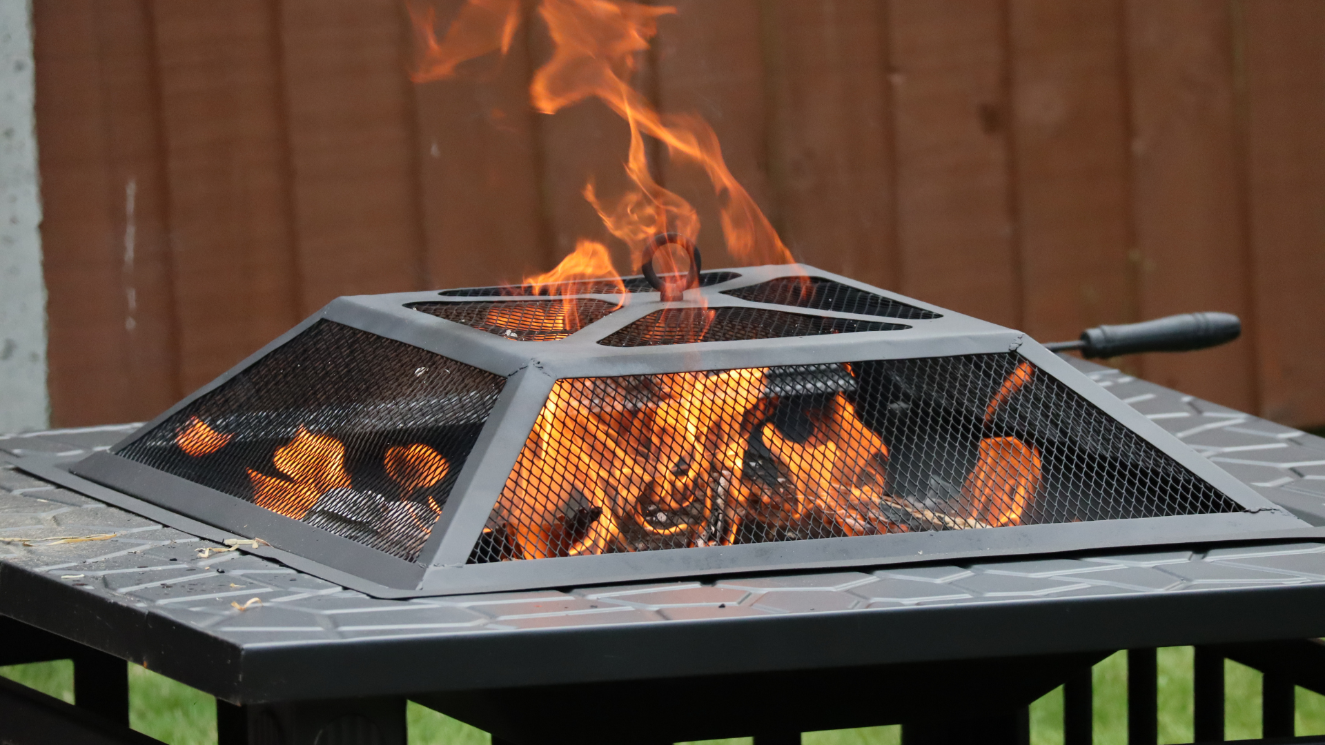 A fire pit with flames coming out of it is on a table.