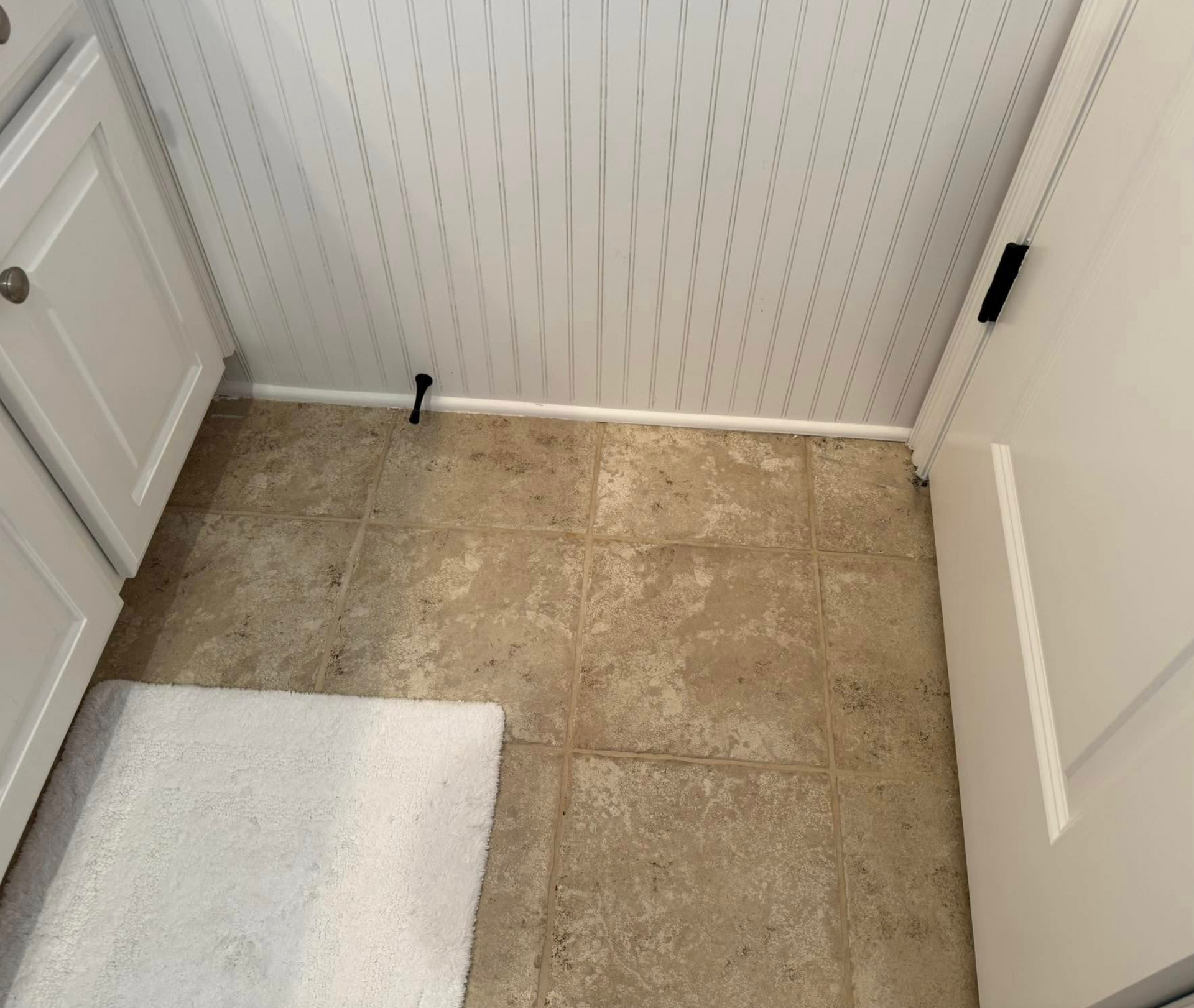 A bathroom with tile floors and white cabinets