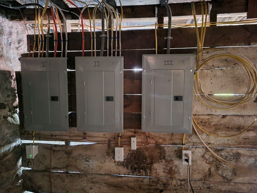 Three electrical panels on a wall with wires coming out of them