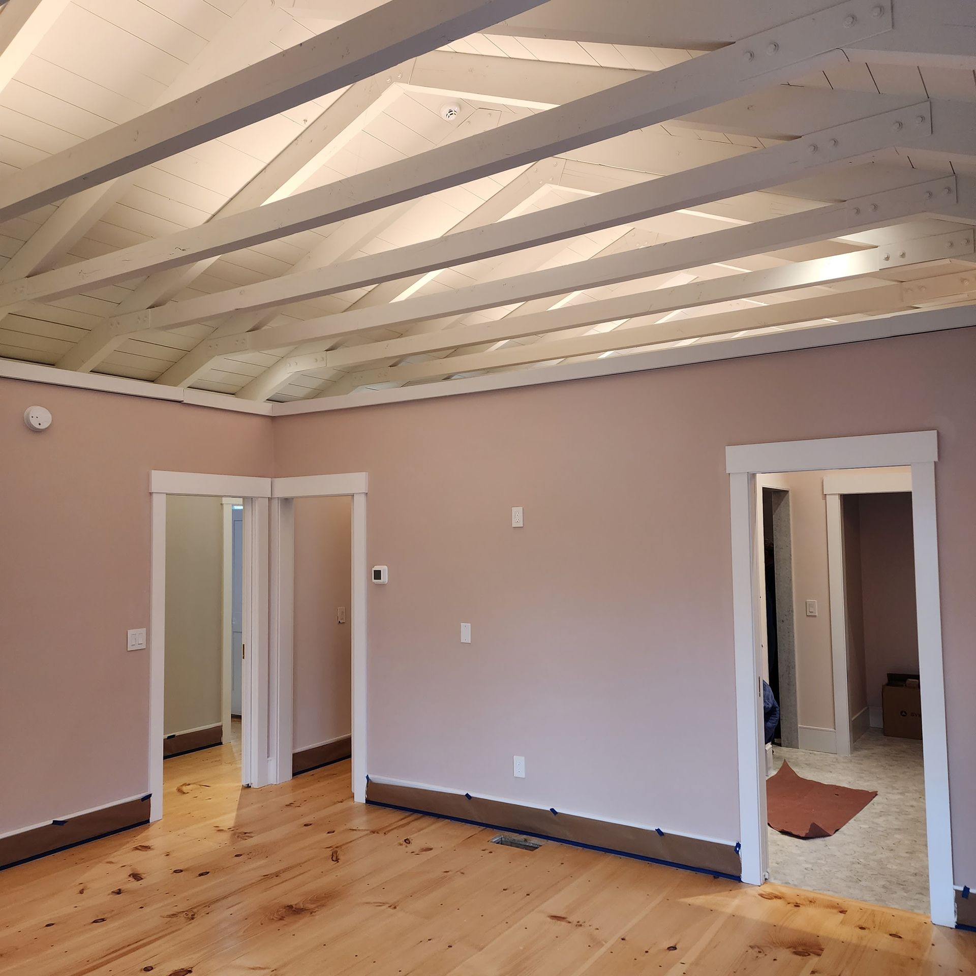 An empty room with wooden floors and white beams