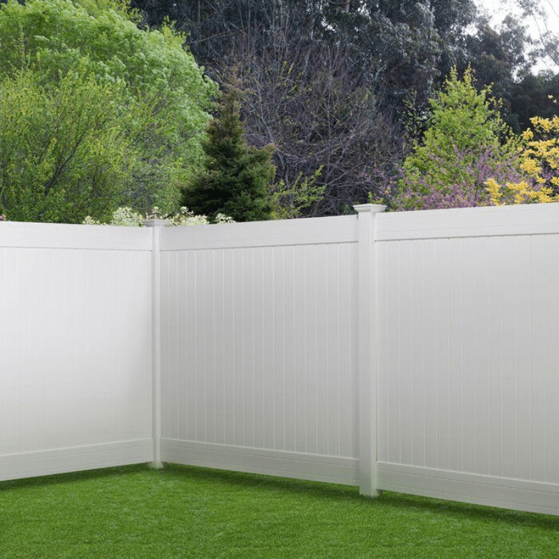 A white vinyl fence surrounds a lush green yard.