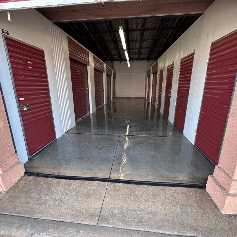 A row of storage units with red doors and a concrete floor