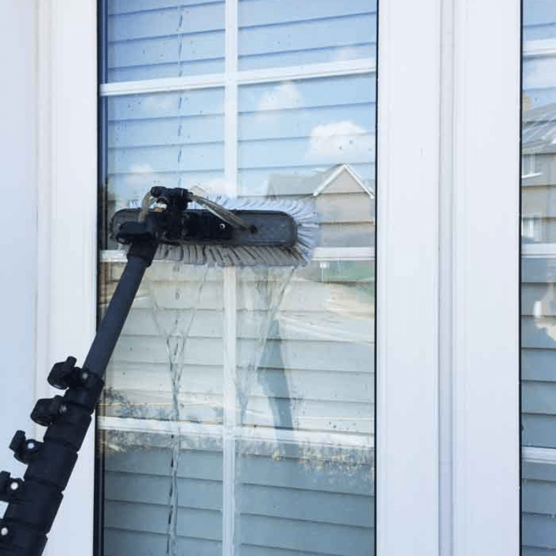 A person is cleaning a window with a mop.