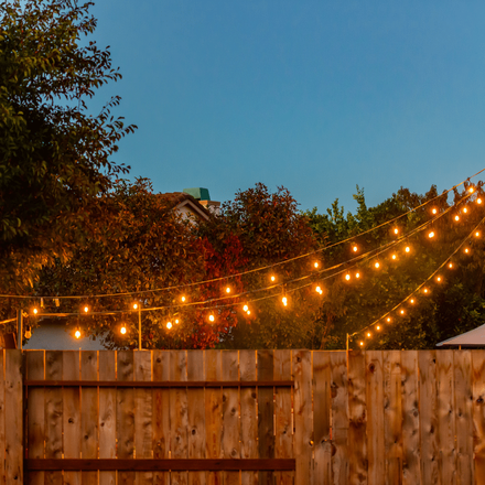 A wooden fence with a string of lights hanging over it.