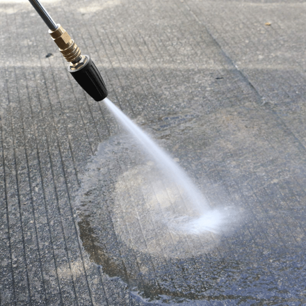 A high pressure washer is spraying water on a concrete surface