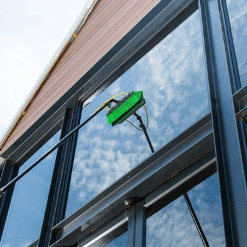 A green brush is being used to clean the windows of a building