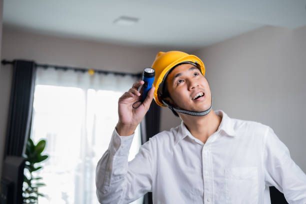 A man wearing a hard hat is holding a flashlight in his hand.