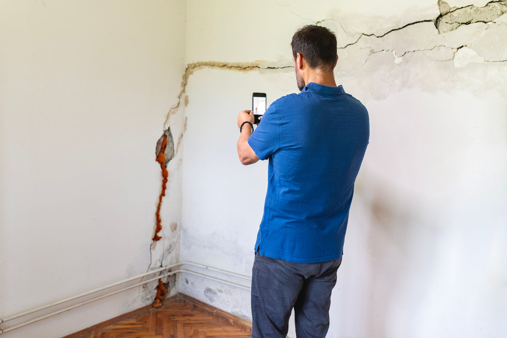 Mature man looking at a wall damaged after the earthquake.