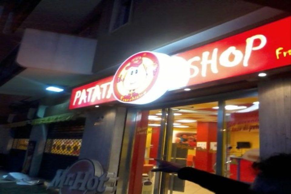insegna luminosa di Patata Shop rossa e gialla