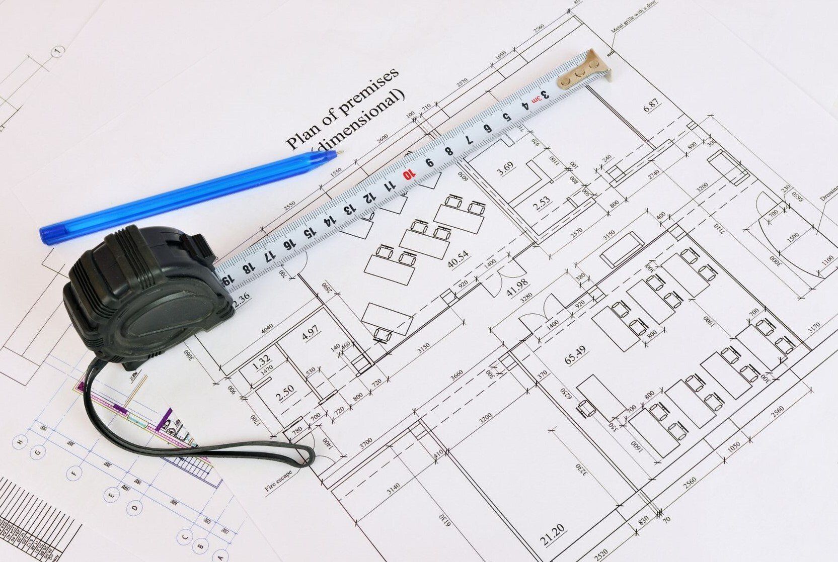 floor plan on table with blue pen and measuring tape on top