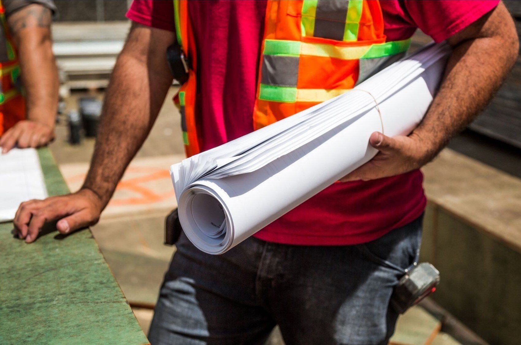 Contractor with architectural drawing rolls on site