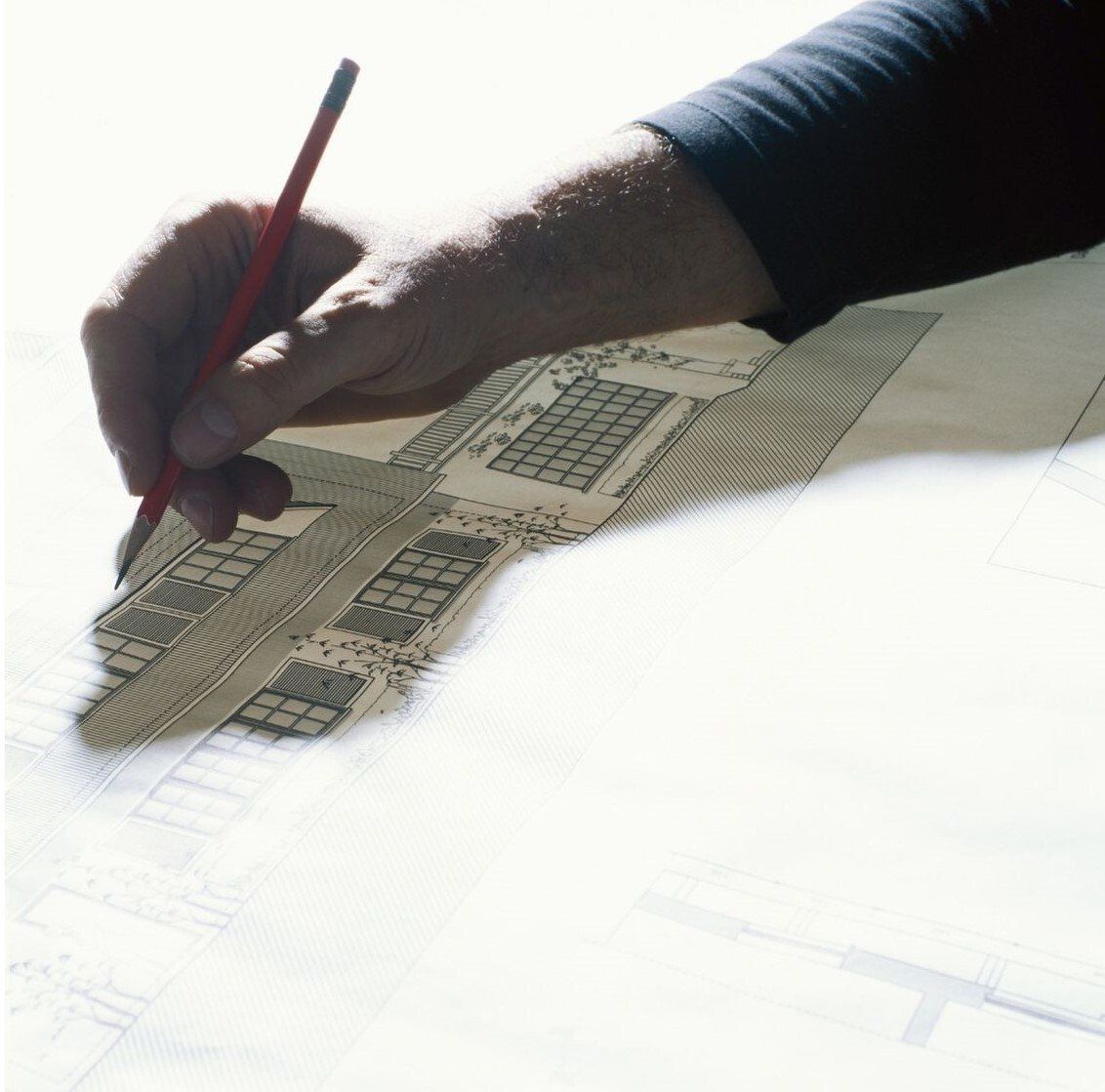 person drawing with pencil on top of CAD elevation drawing