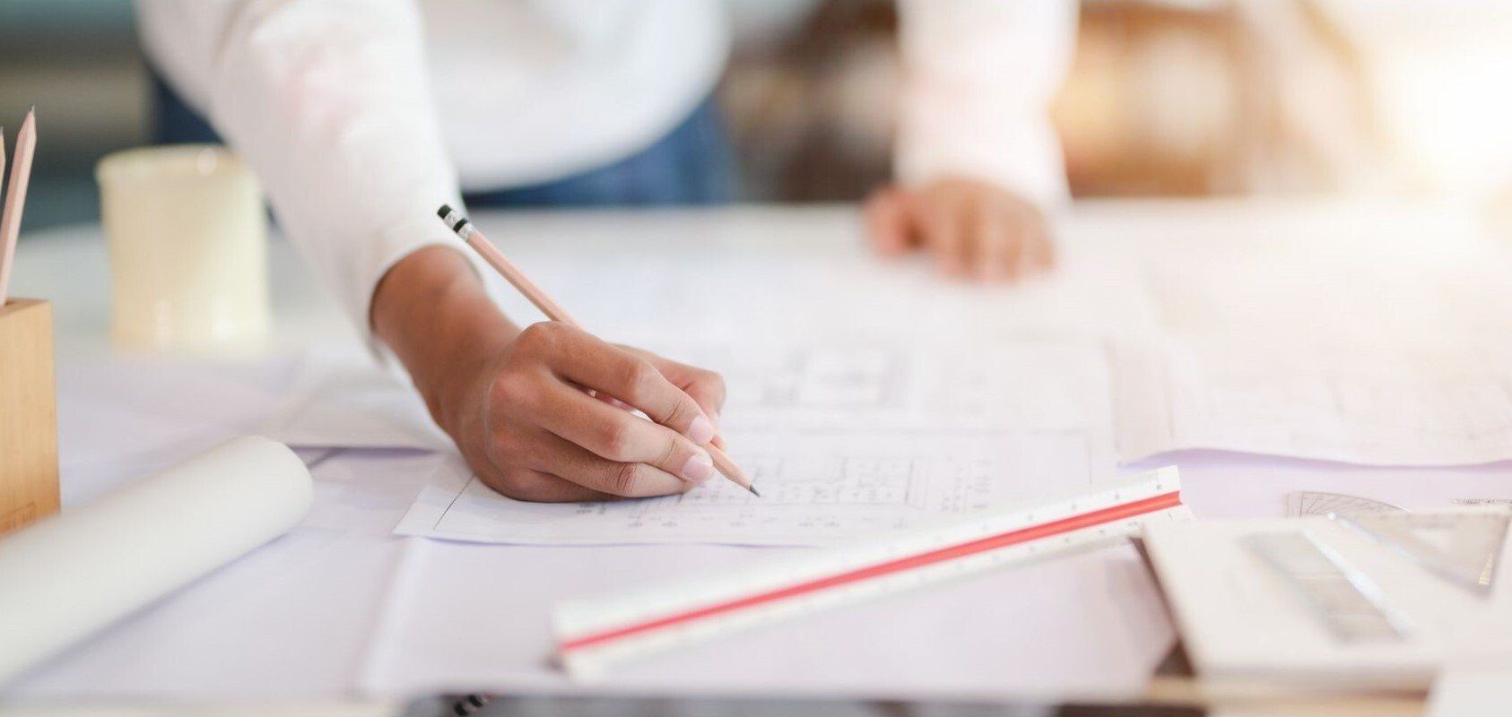 person drawing on large white paper with red scale
