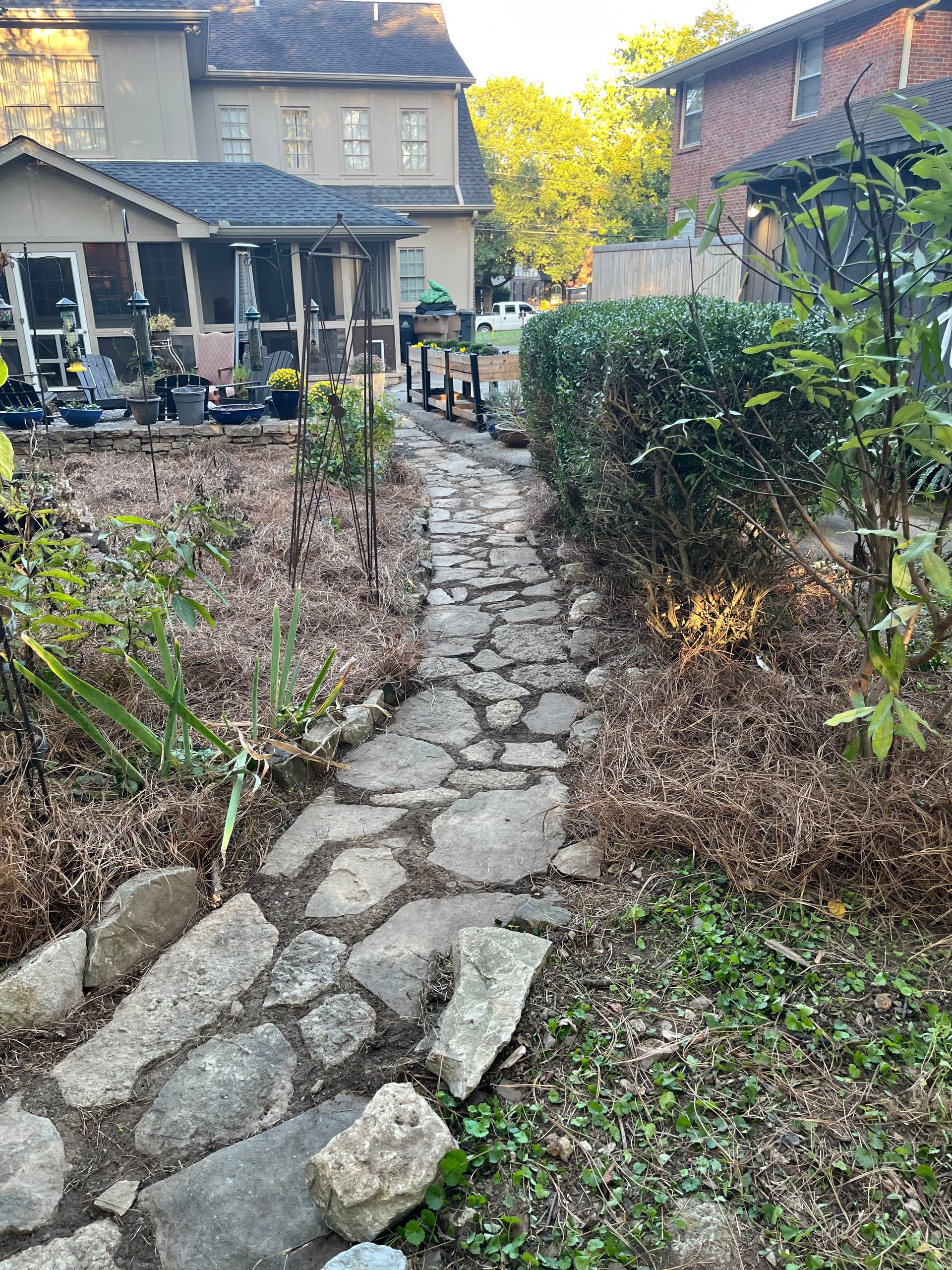 A stone walkway leading to a house in a backyard.