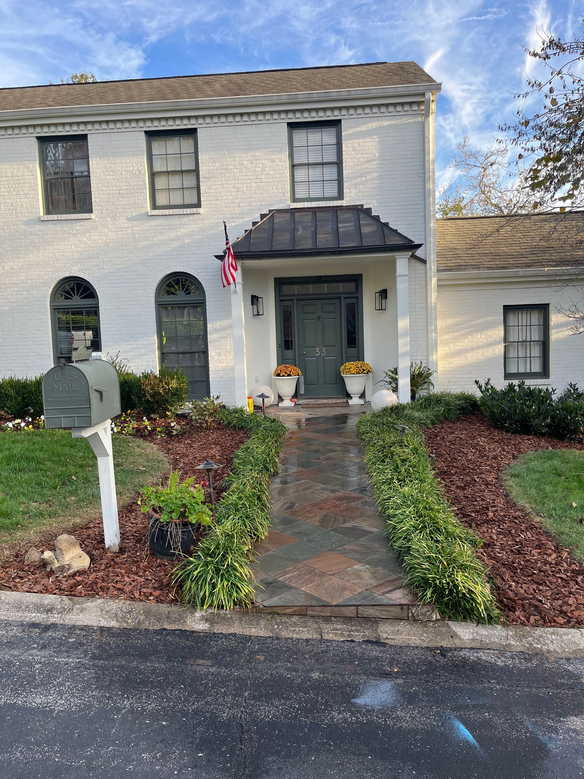 A white brick house with a mailbox in front of it.