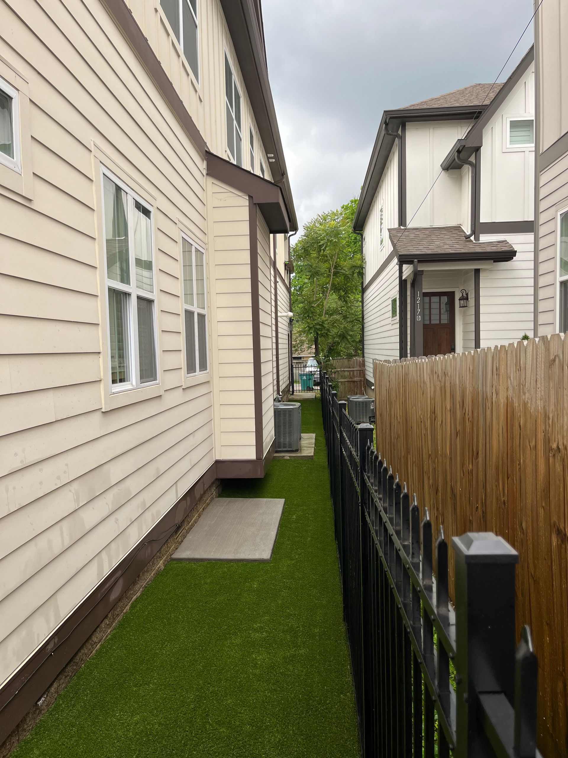 A narrow alleyway between two houses with a wooden fence